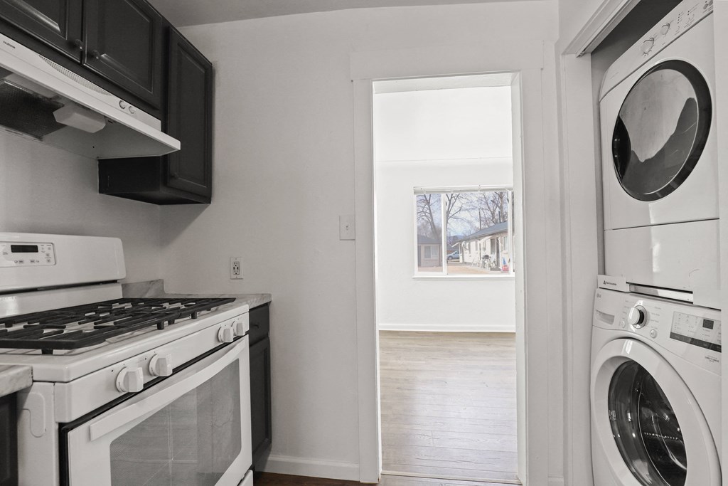 an empty kitchen with a washer and dryer and a window