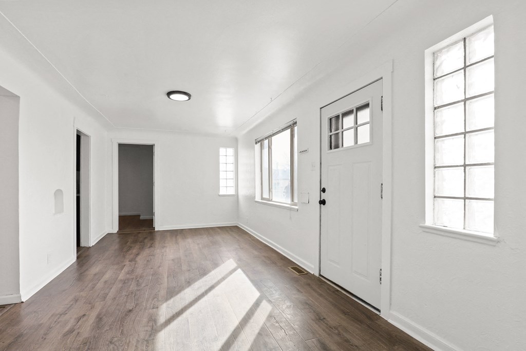 an empty living room with white walls and a white door