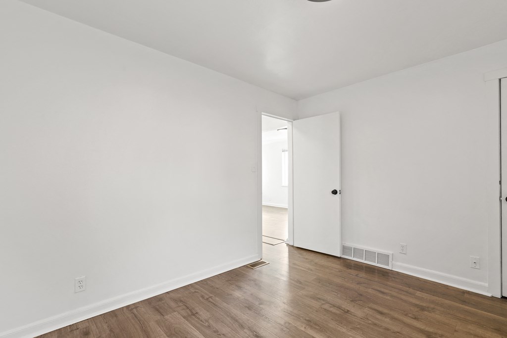 an empty living room with white walls and wood floors
