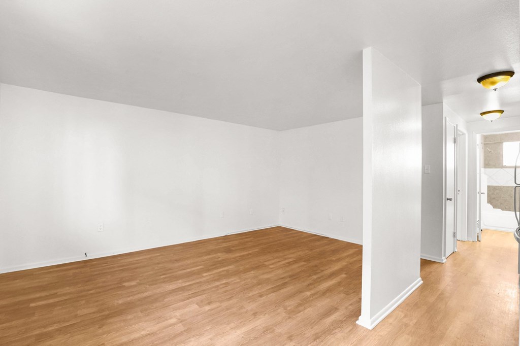 the living room and dining room of an apartment with wood floors and white walls