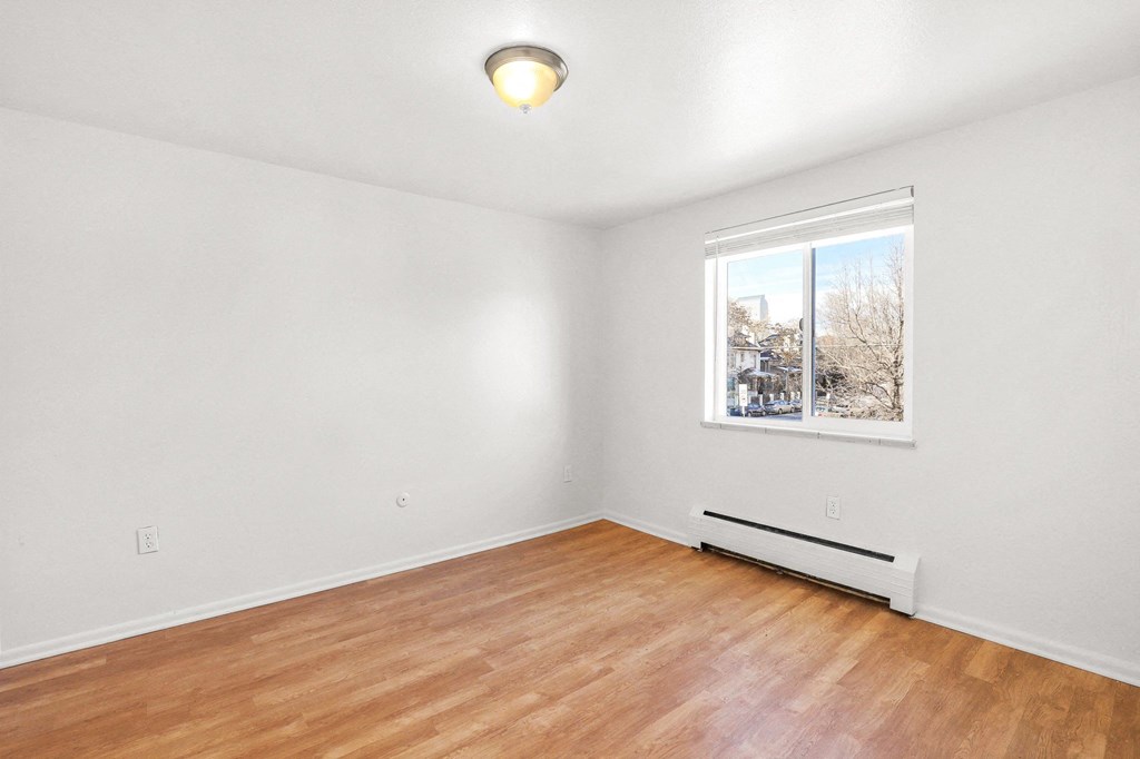an empty living room with wood floors and a window