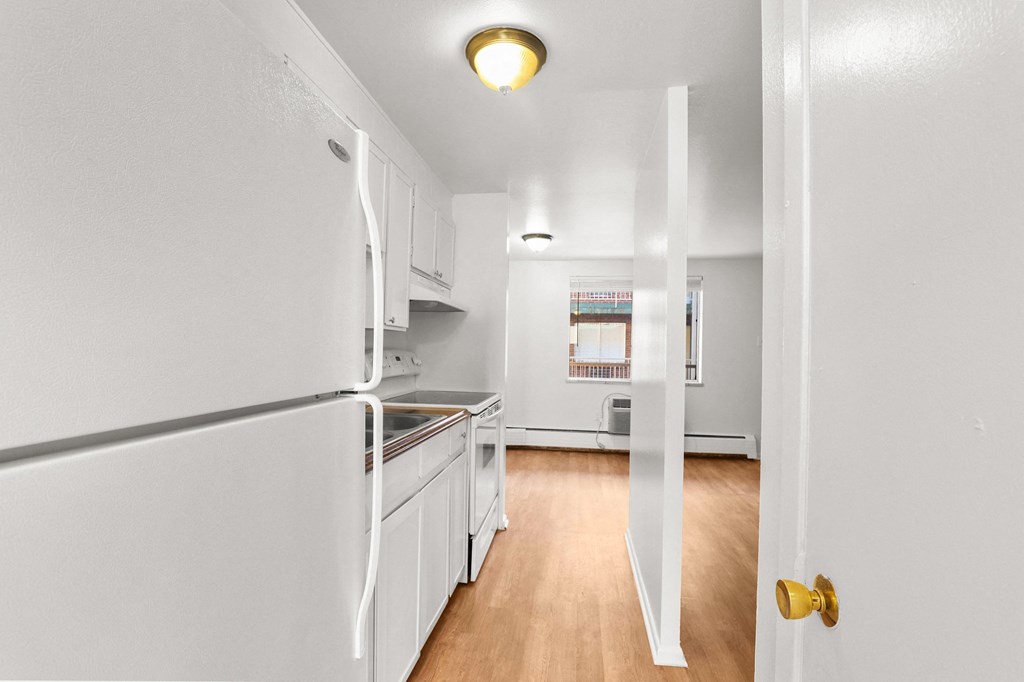 the view of a kitchen with white appliances and wood flooring