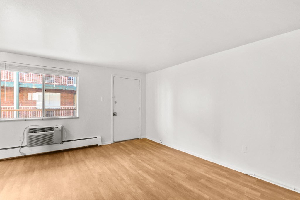 the living room of an apartment with wood flooring and a window