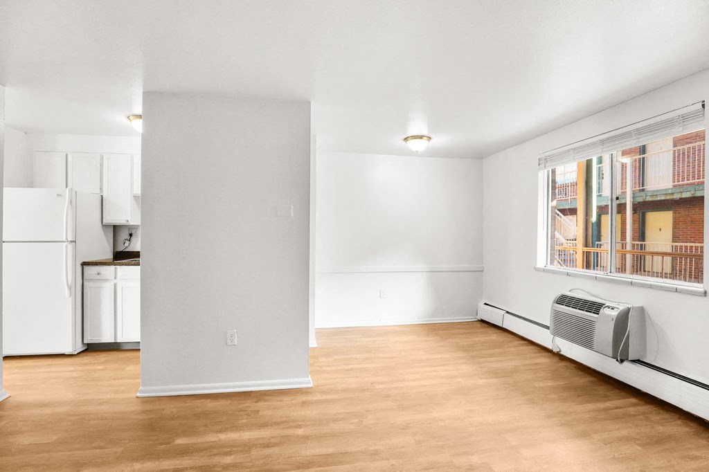 a living room with white walls and a window and a kitchen