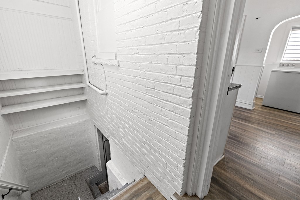 the corner of a room with a white brick wall and wood floors