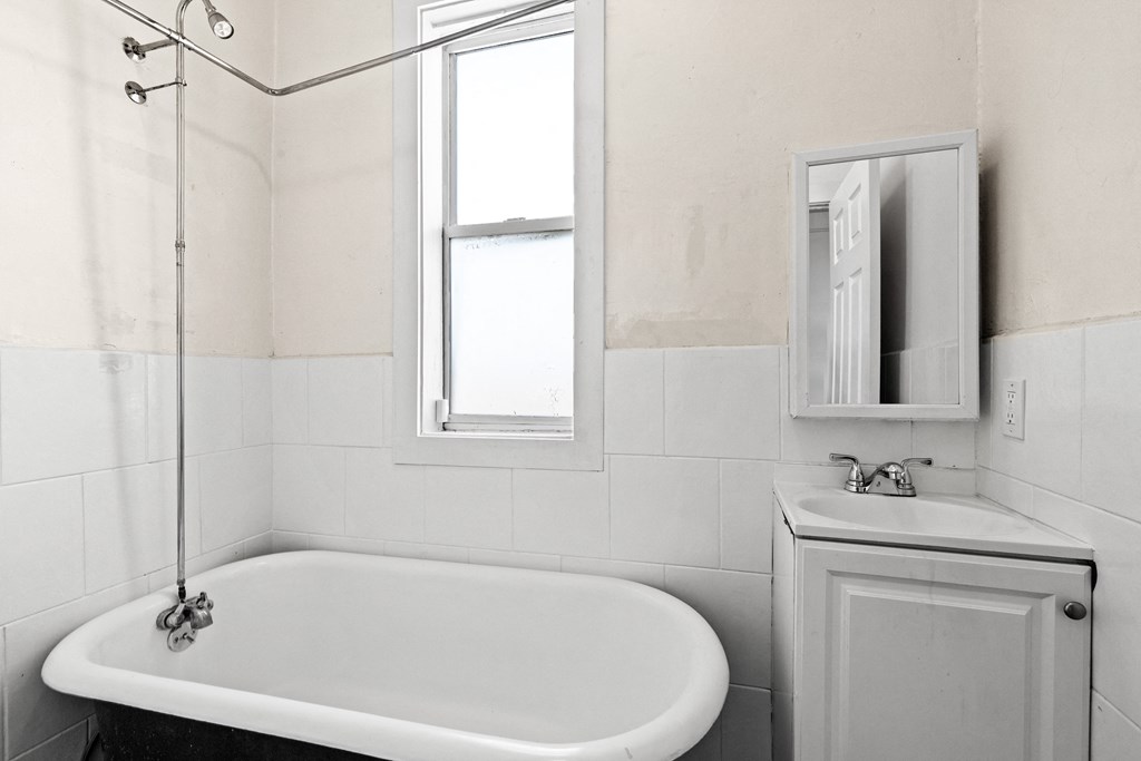 a small white bathroom with a tub and a sink