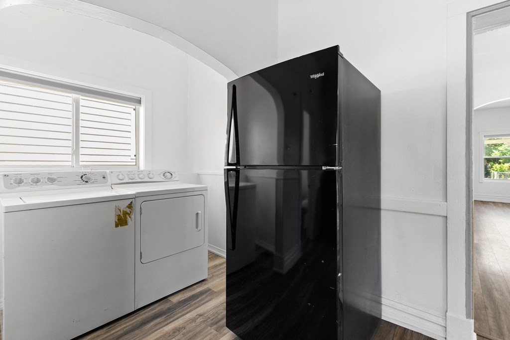 a white kitchen with a black refrigerator and white appliances