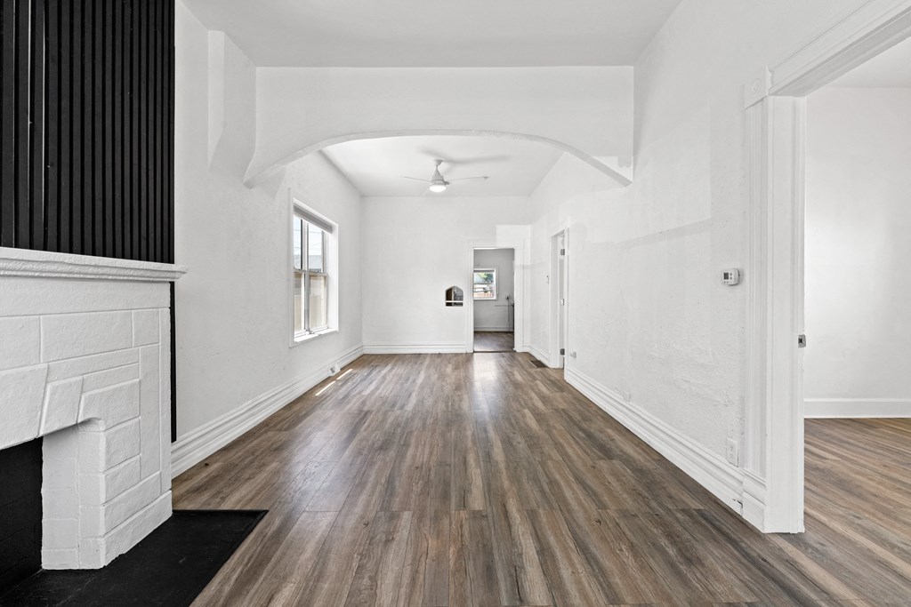 a living room with white walls and wood floors and a fireplace