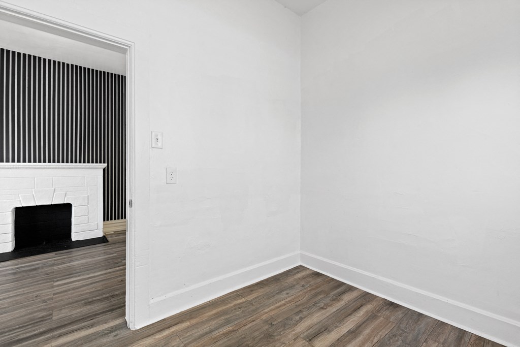 a living room with white walls and a fireplace and wooden floors