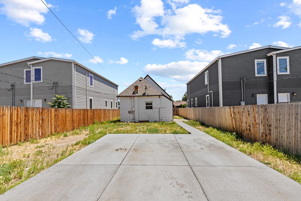 the back yard of a house with a sidewalk and a fence