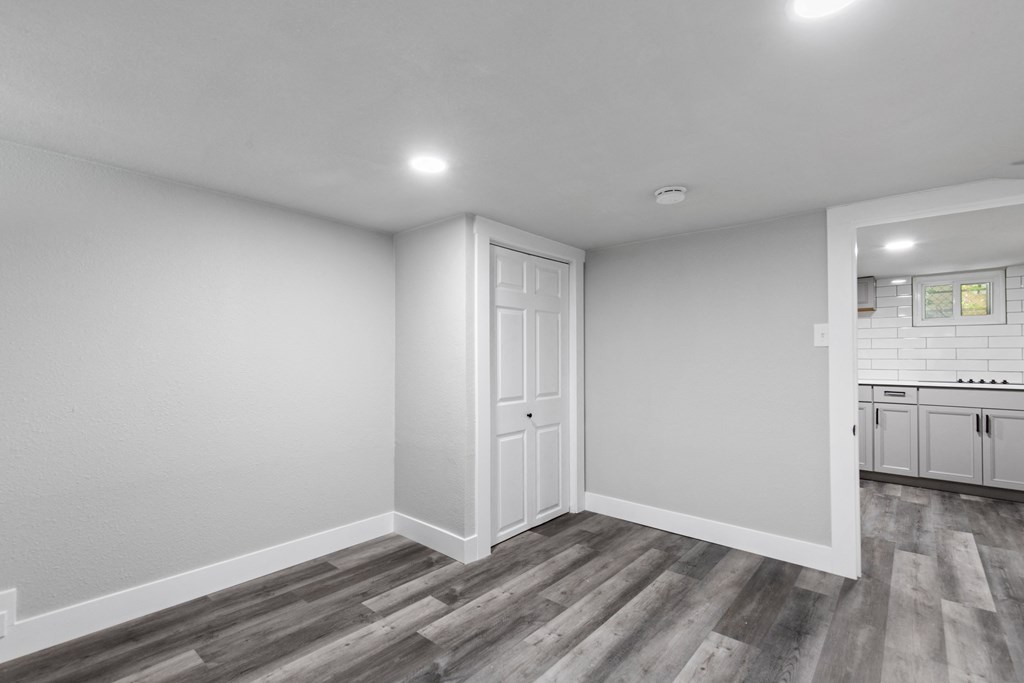 the living room and kitchen in a new home with white walls and wood flooring