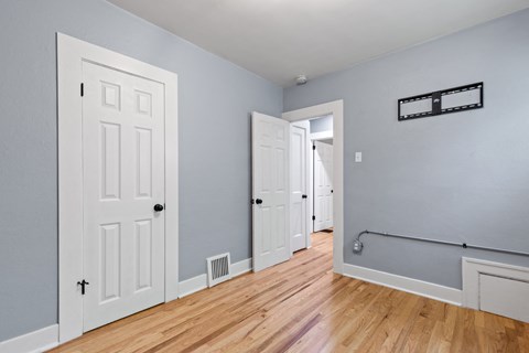 an empty room with three doors and a wood floor