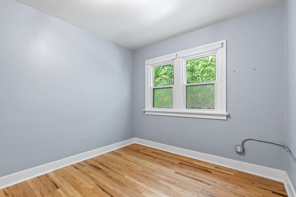 an empty room with wood floors and a window