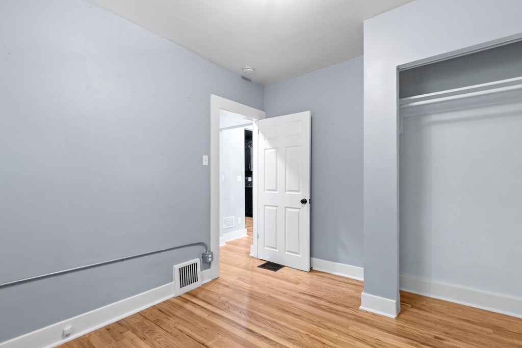 a bedroom with grey walls and wood floors and a white door