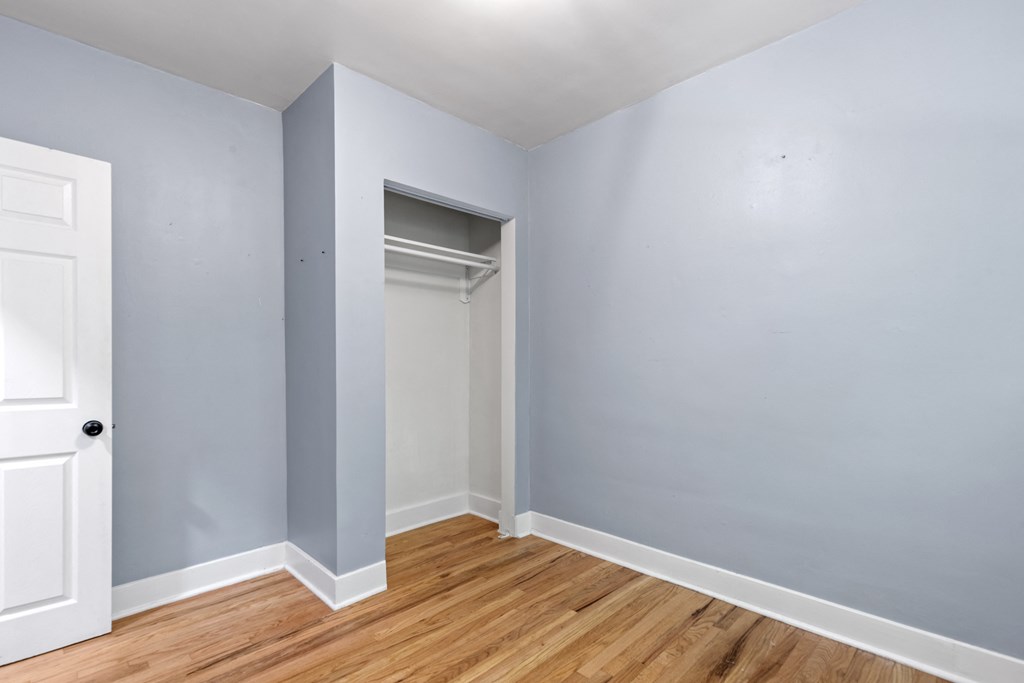 an empty room with blue walls and wood floors and a closet