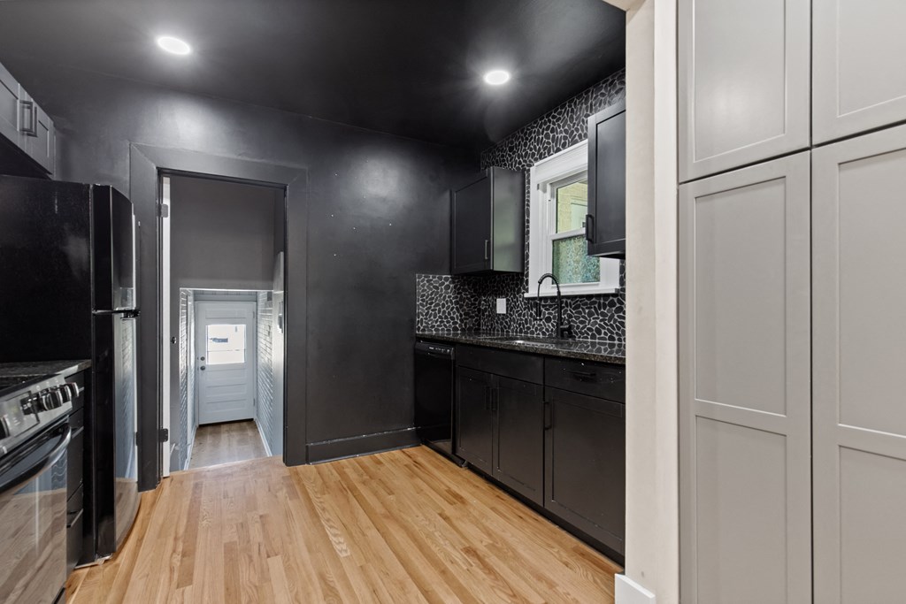 a kitchen with black and white cabinets and a wood floor
