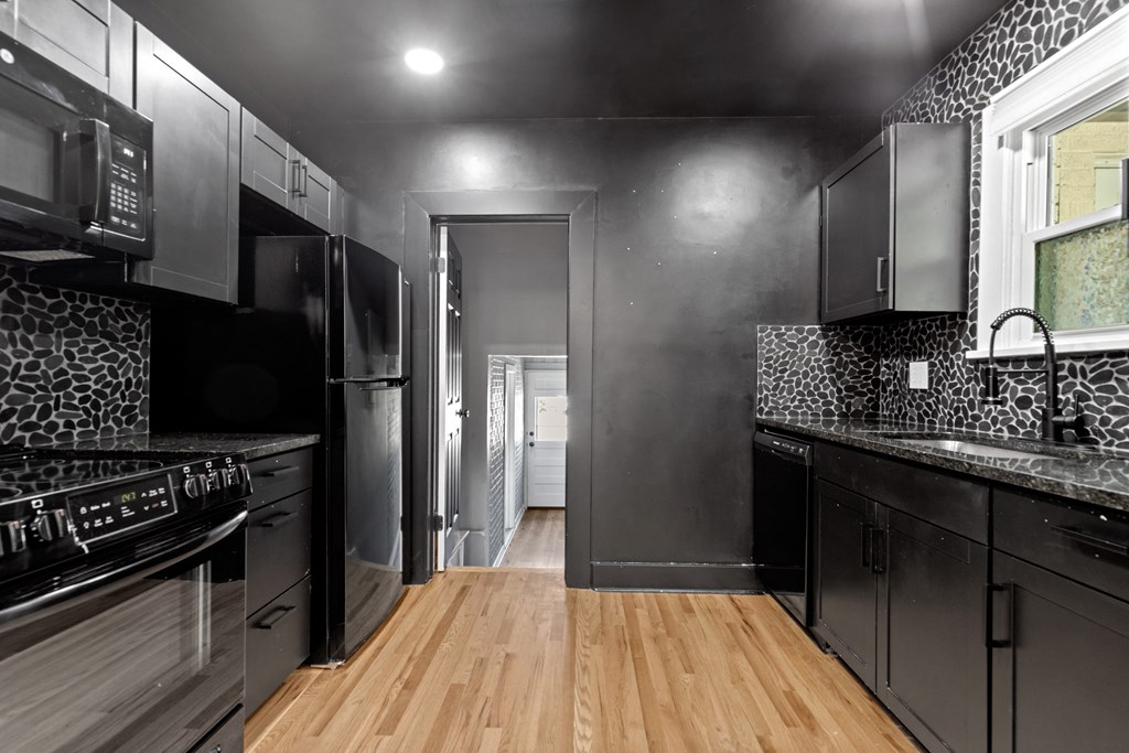 a kitchen with black cabinets and stainless steel appliances