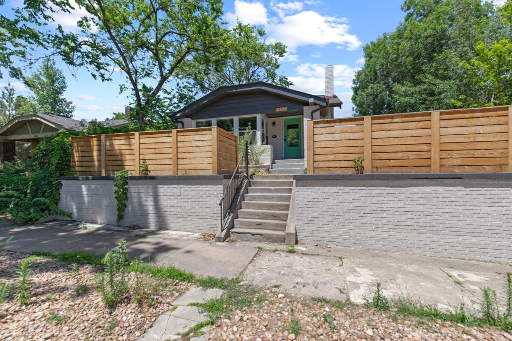 the front of a house with a brick wall and a wooden fence