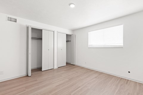 the living room of an apartment with white walls and wood flooring