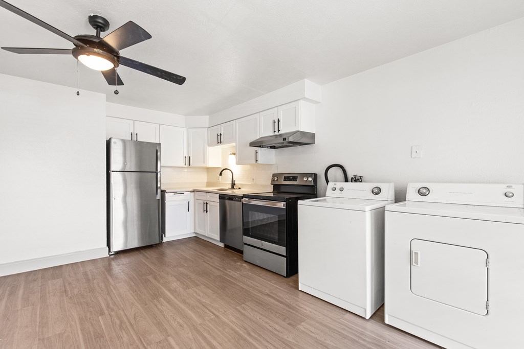 a white kitchen with stainless steel appliances and a ceiling fan