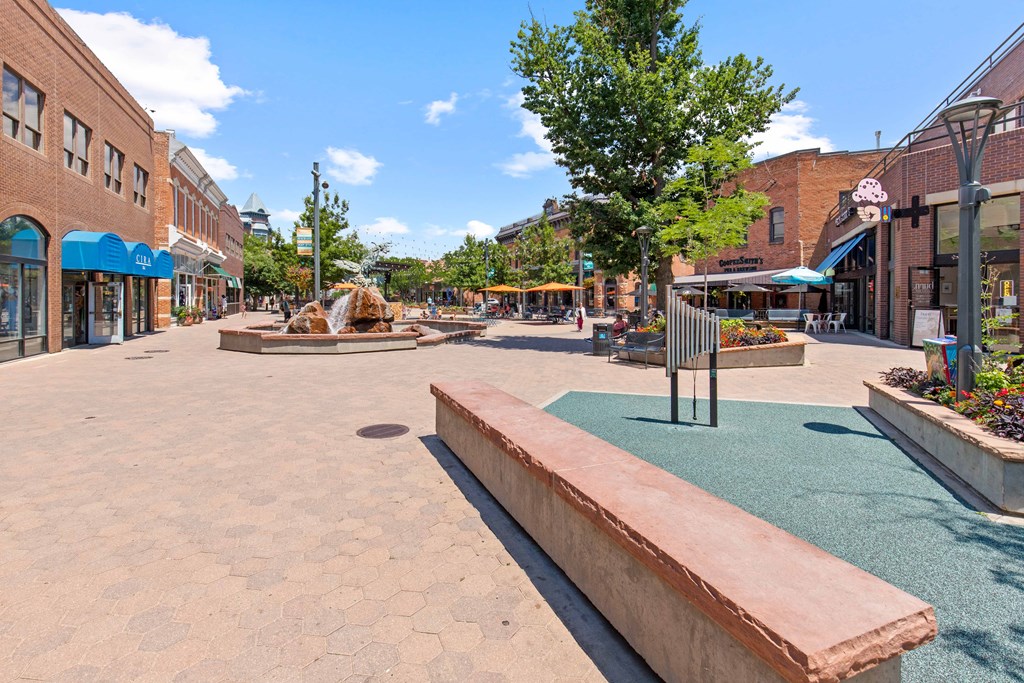 a park with a fountain in the middle of a city street