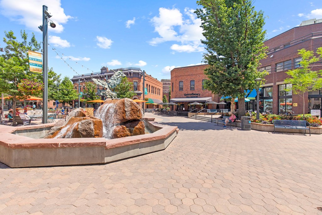 A fountain in the middle of a plaza with people sitting around it.