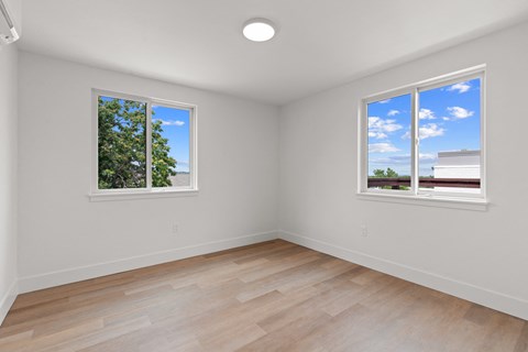 a living room with two windows and a wooden floor