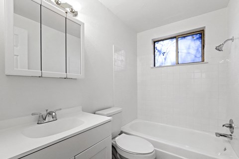 A white bathroom with a sink, toilet, and bathtub.