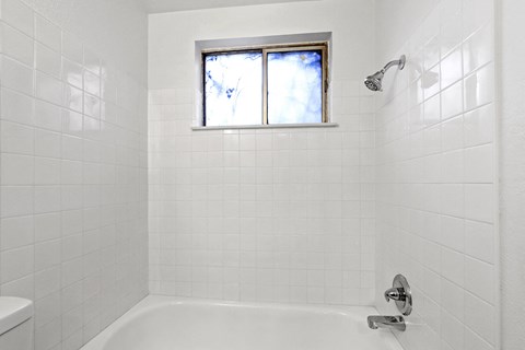 A white tiled bathroom with a window.