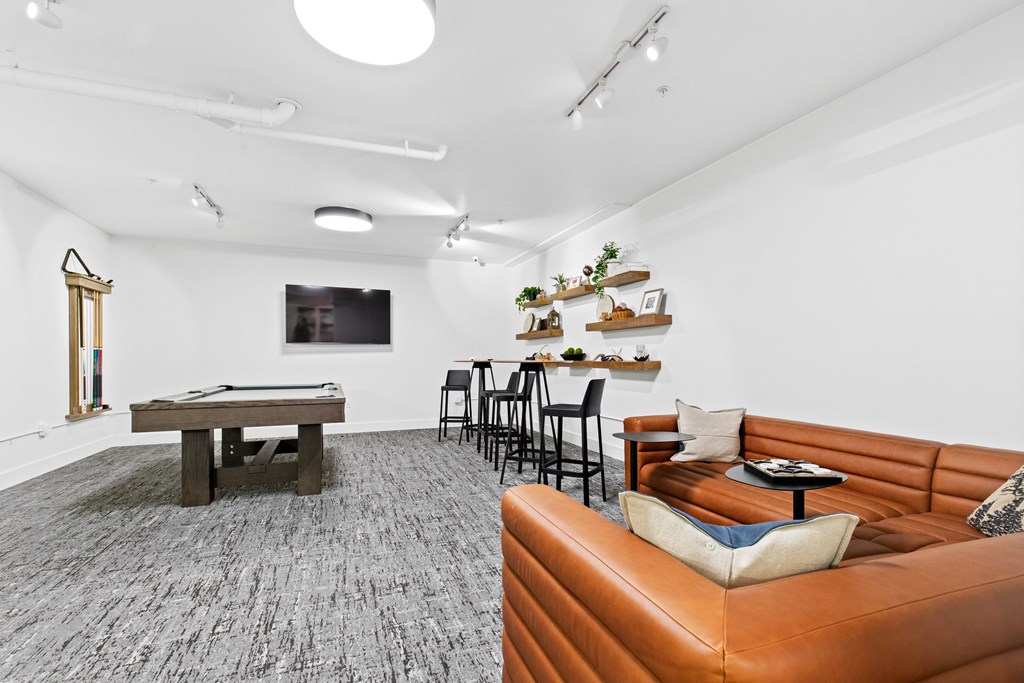 a living room with a leather couch and a pool table