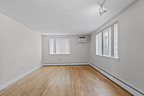 an empty living room with wood flooring and a window