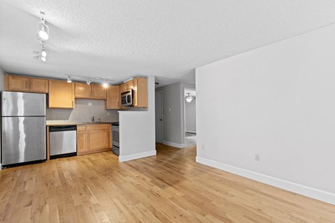 an empty kitchen with wood flooring and stainless steel appliances