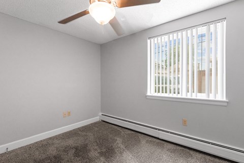 an empty bedroom with a ceiling fan and a window