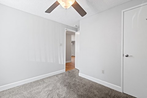 a bedroom with white walls and a ceiling fan