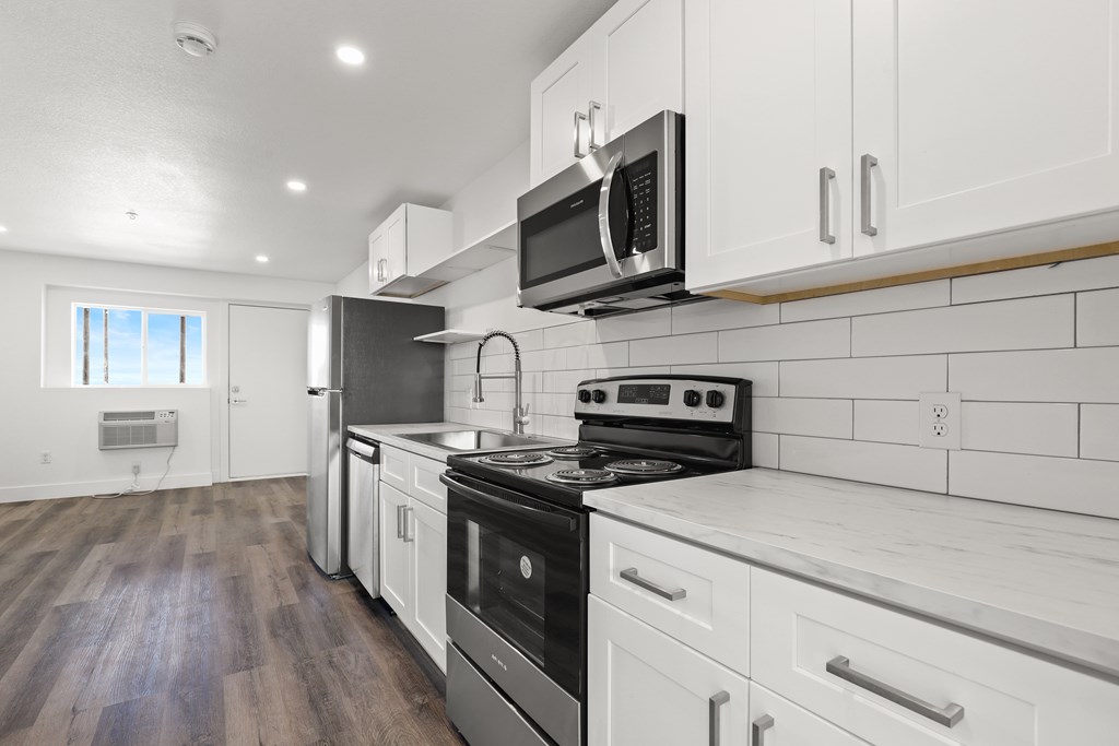 an empty kitchen with white cabinets and a stove and microwave