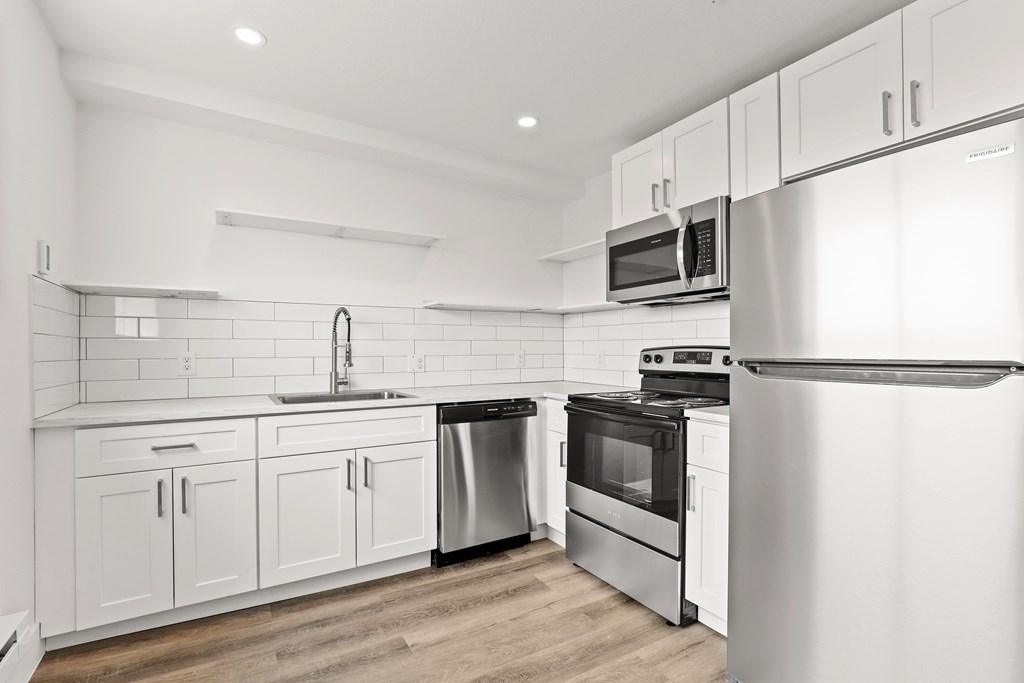 a white kitchen with stainless steel appliances and white cabinets