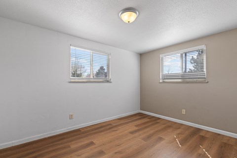 A room with wooden floors and two windows.