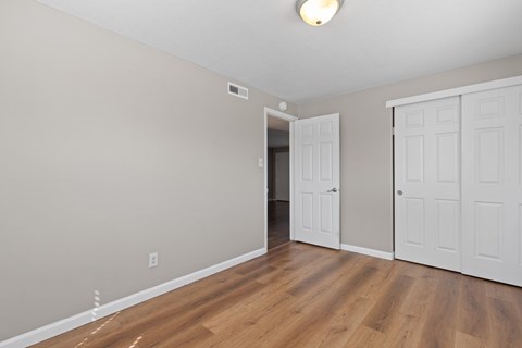 A room with a white door and a wooden floor.