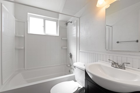 A white bathroom with a tub, toilet, and sink.