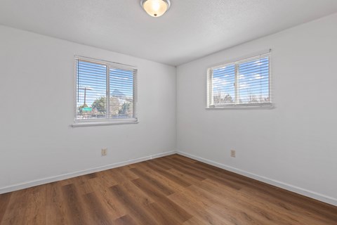 A room with wooden floors and two windows.