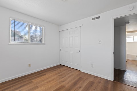 A room with a white door and a window with blinds.