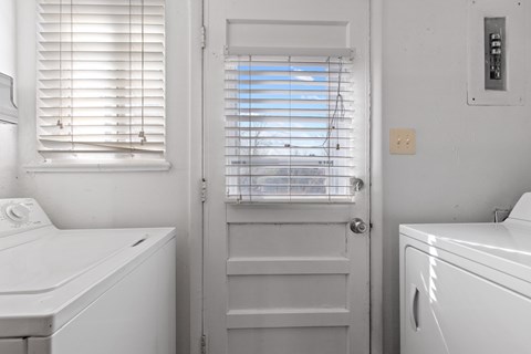A white bathroom with a washing machine and a door.
