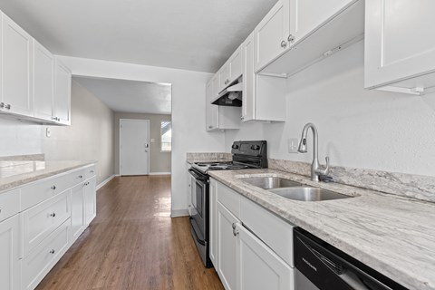 A kitchen with white cabinets and a marble countertop.