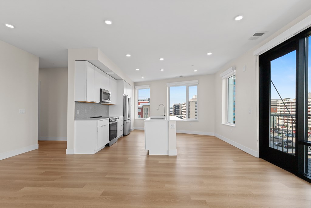 A spacious kitchen with white cabinets and a wooden floor.