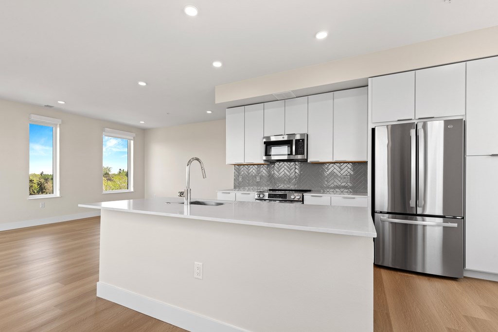 A modern kitchen with white cabinets and stainless steel appliances.