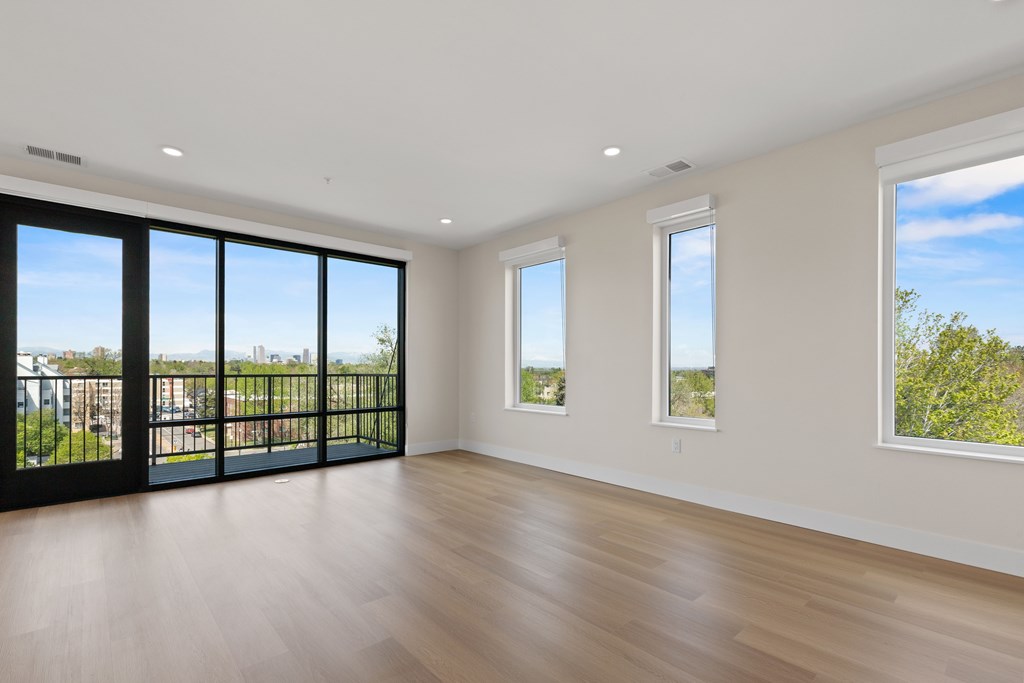 A large empty room with wooden floors and windows.