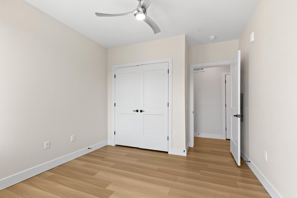 A room with a white door and a ceiling fan.