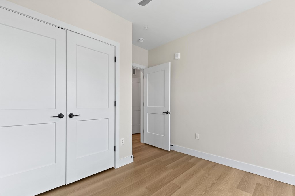 A room with two white doors and a wooden floor.