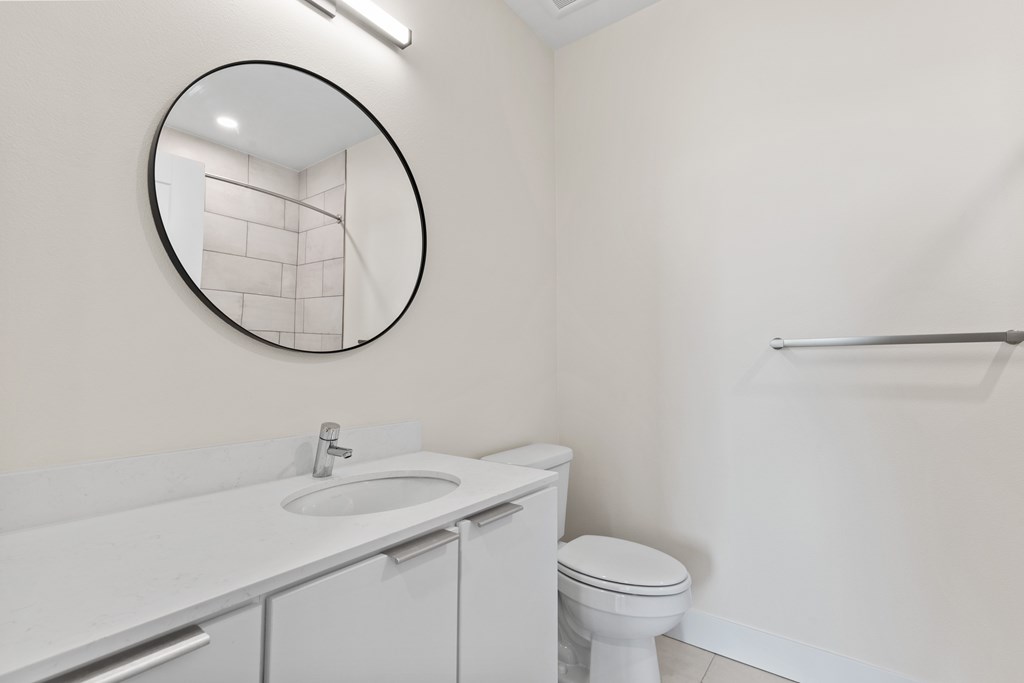 A white bathroom with a toilet, sink, and mirror.