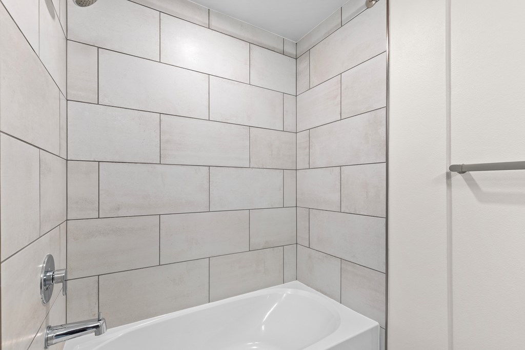 A white bathtub with a shower head attached to the wall.